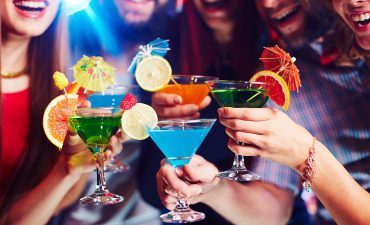 Colourful cocktails in the hands of cruisers to illustrate minimum drinks packages