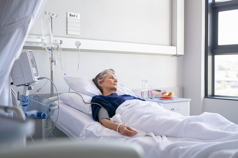 Sad senior woman lying on hospital bed