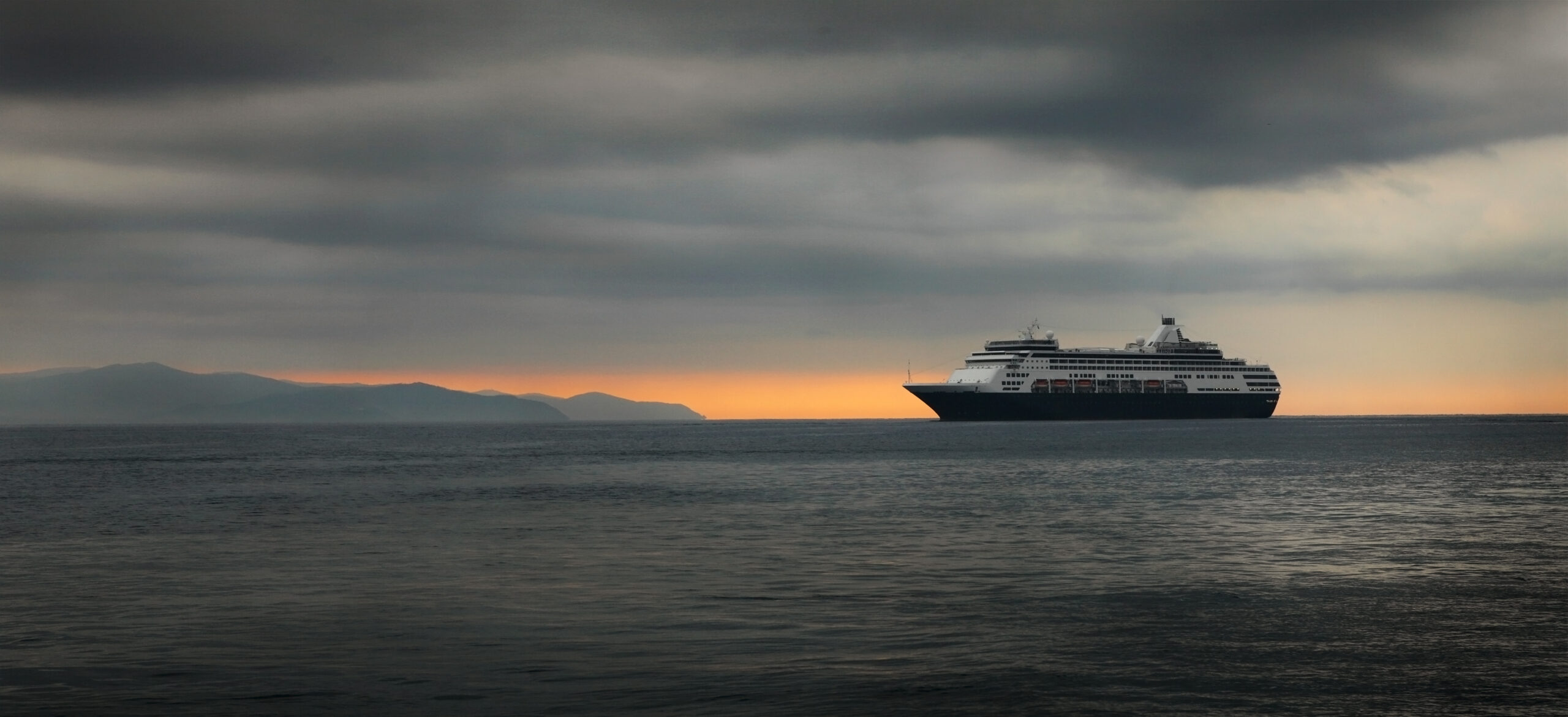Big cruise ship in a grey water at the sunrise