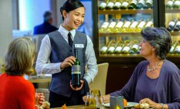 A sever with a bottle of wine with two ladies on a Viking Ocean