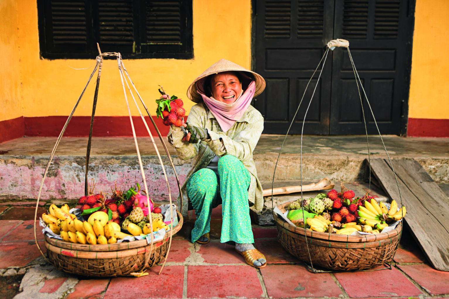 Vietnamese woman carrying fruits for sale in Hoi An town, Vietnam.