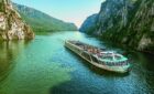 An exterior view of AmaMagna sailing through a gorge. It is twice the width of almost every other river ship in Europe.