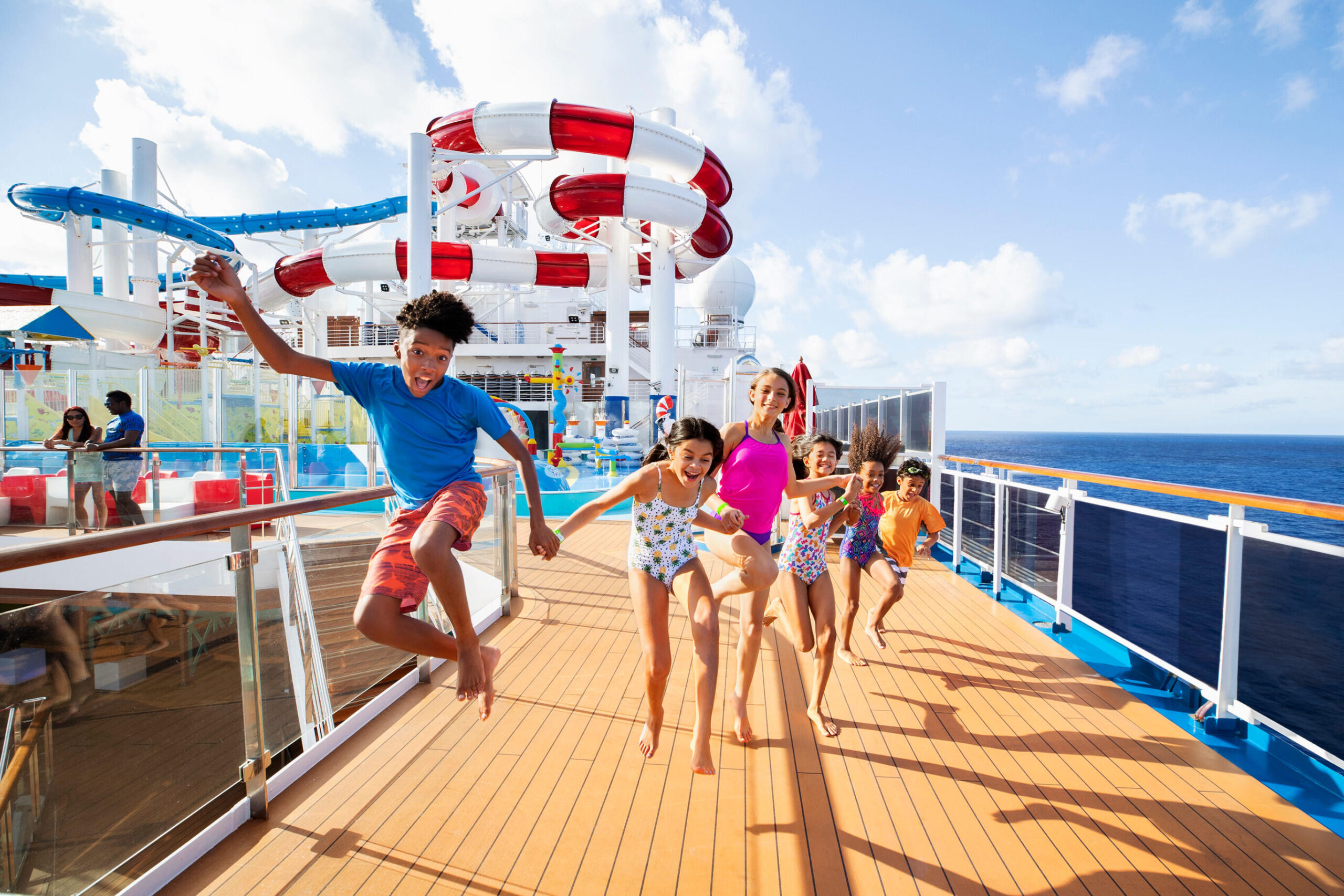 Kids on a Carnival ship with a waterslide in the background on an affordable family holiday