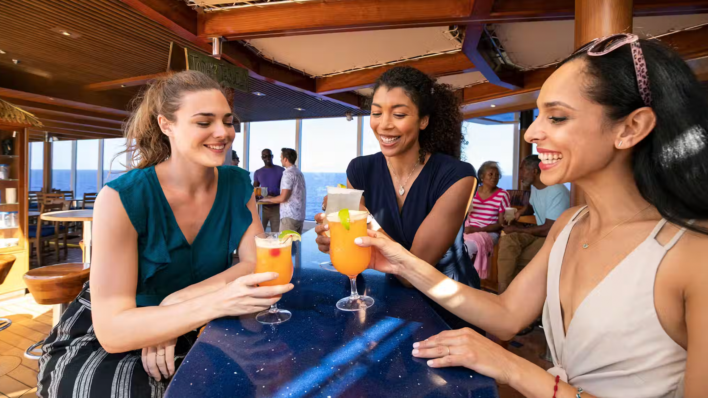 Three girls drinking cocktails on a Carnival ship