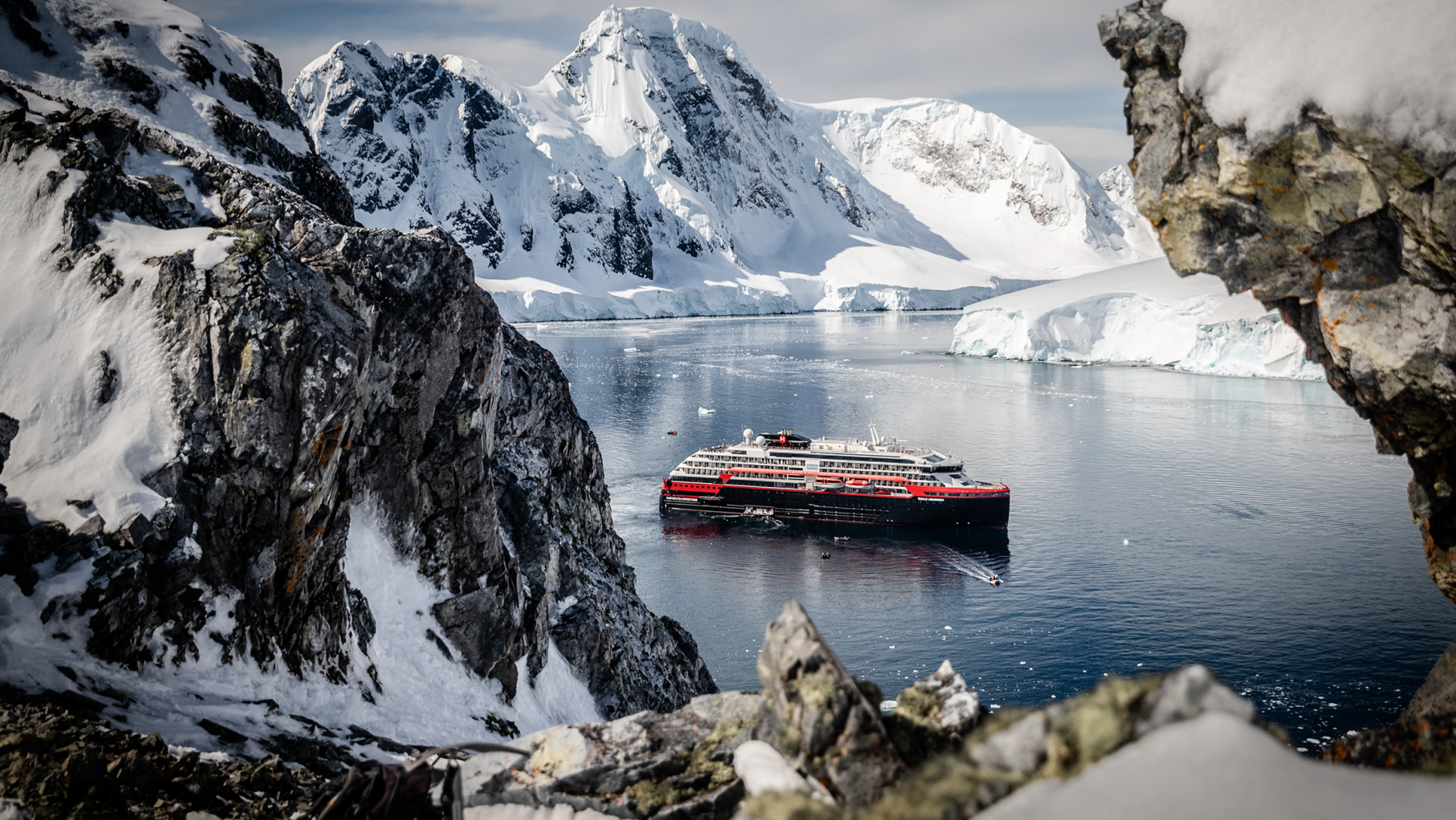 A Hurtigruten ship in Antarctica surrounded by snow mountains