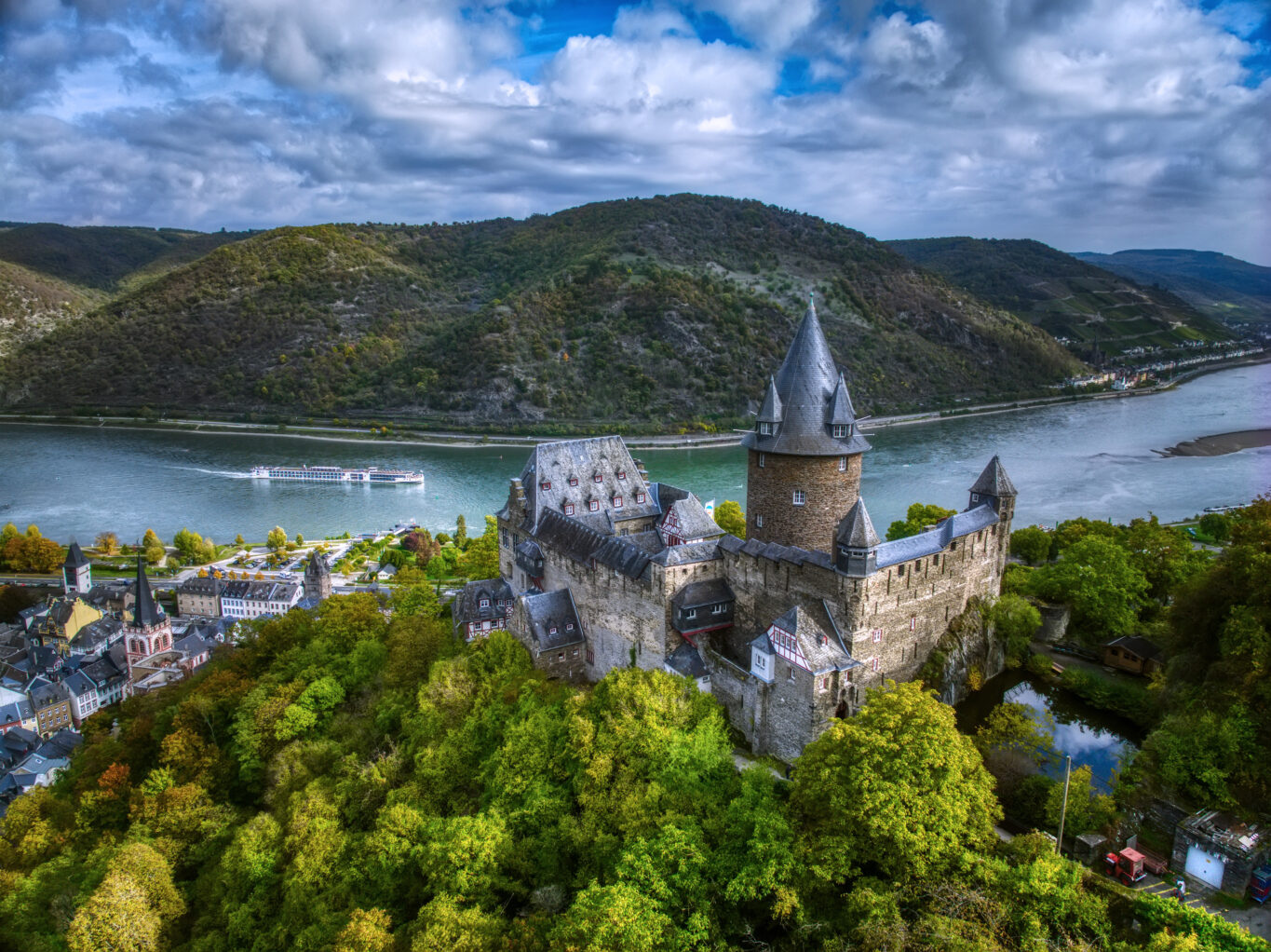 Viking Longship Gymir on the Rhine River with Stahleck Castle (German: Burg Stahleck) a 12th-century fortified castle in the Upper Middle Rhine Valley at Bacharach in Rhineland-Palatinate, Germany. It stands on a crag approximately 160 metres (520 ft) above sea level on the left bank of the river at the mouth of the Steeg valley, approximately 50 kilometres (31 mi) south of Koblenz, and offers a commanding view of the Lorelei valley in Germany.