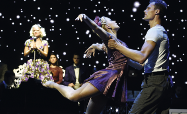 Two dancers performing on stage with a singer on Regent Seven Seas