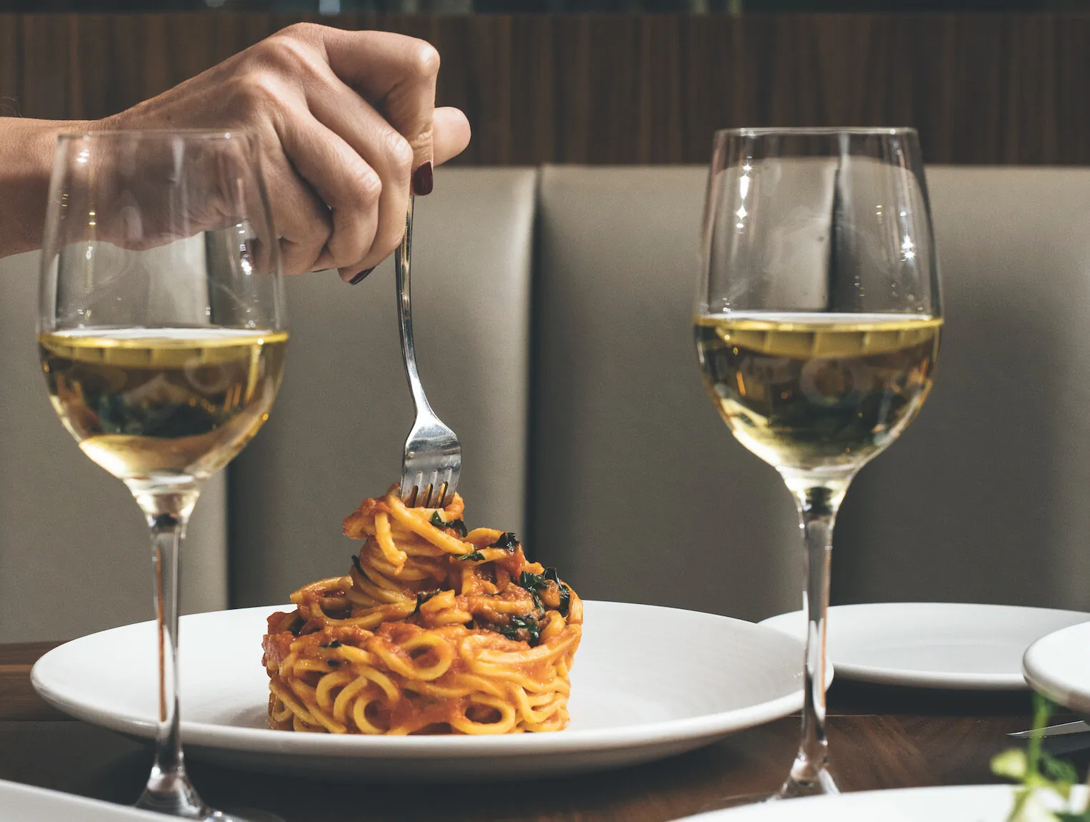 A spaghetti dish and two glasses of wine at Onda by Scarpetta on Norwegian Cruise Line Prima class