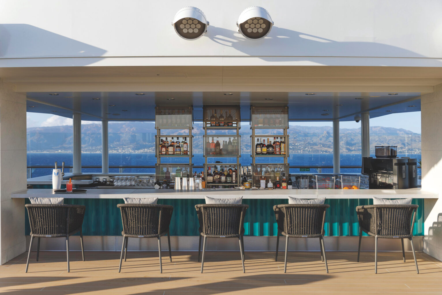 The Silver Nova Pool Bar with chairs facing a bar and blue sea int he bakground.