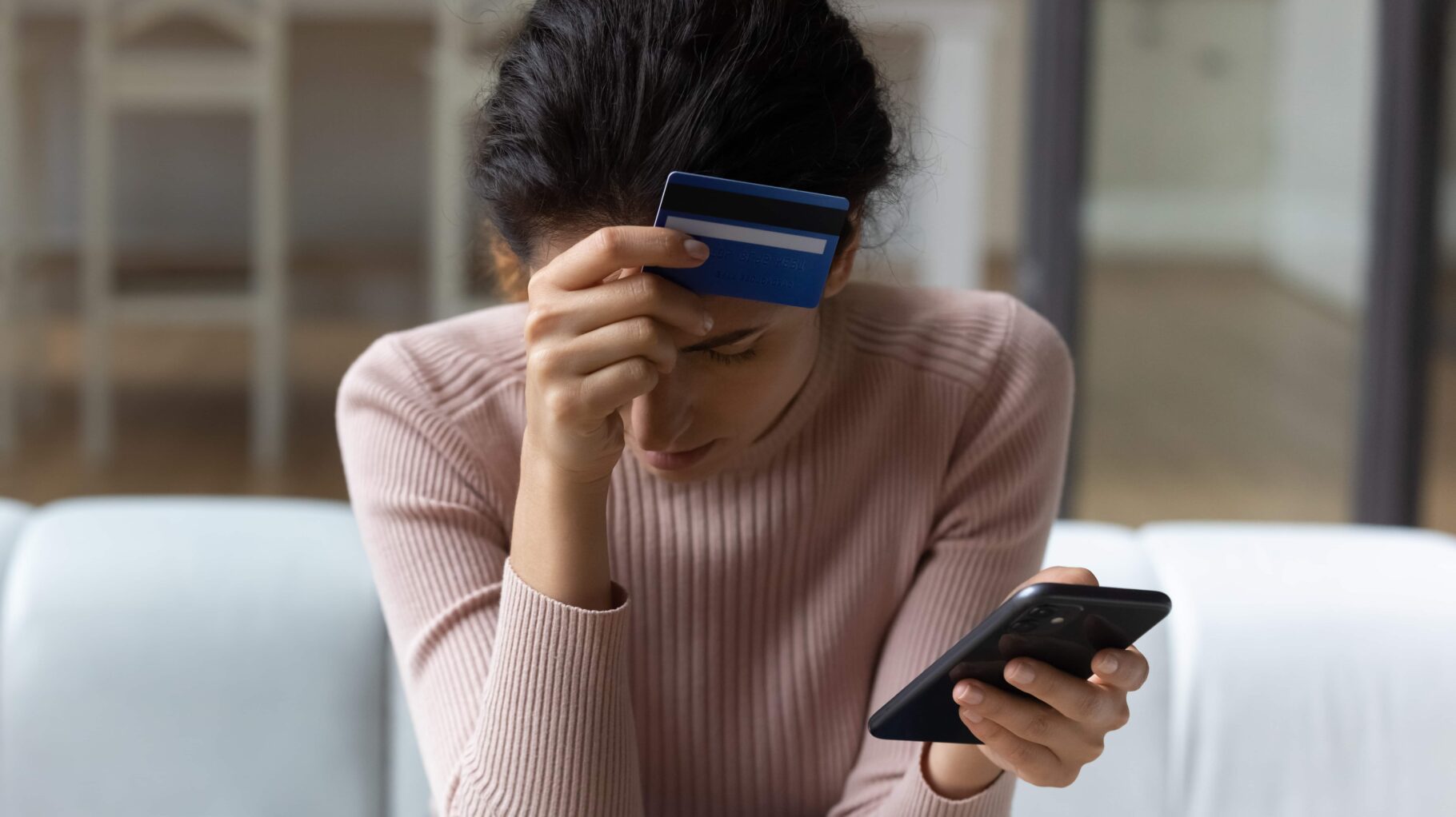 women holding credit card to her head after being scammed