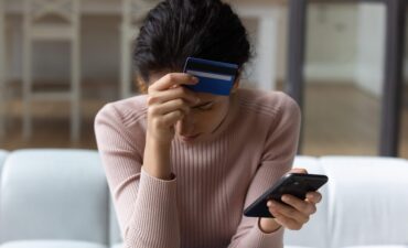 women holding credit card to her head after being scammed