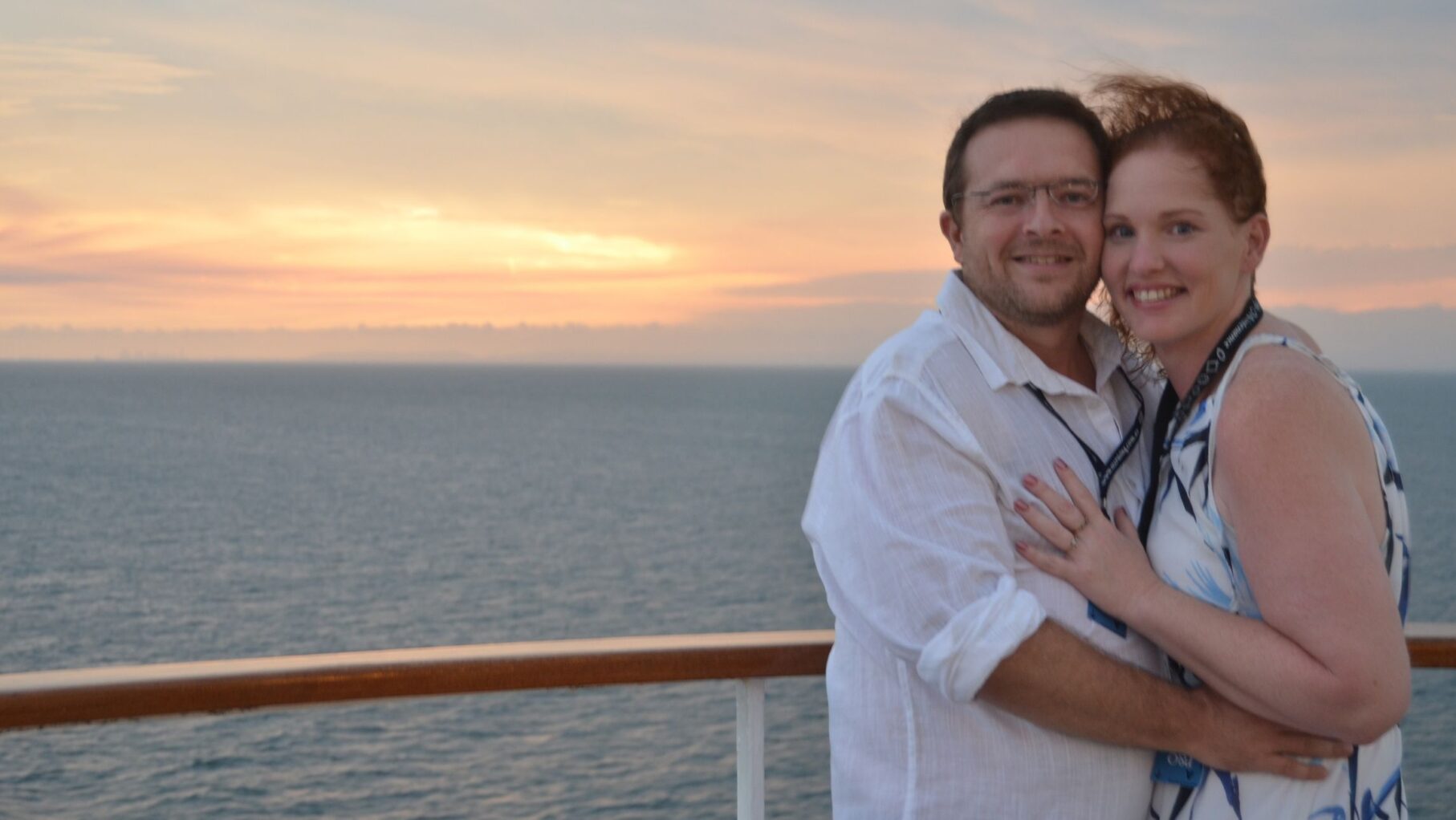 The newly engaged couple pose for a photo by the sunset.