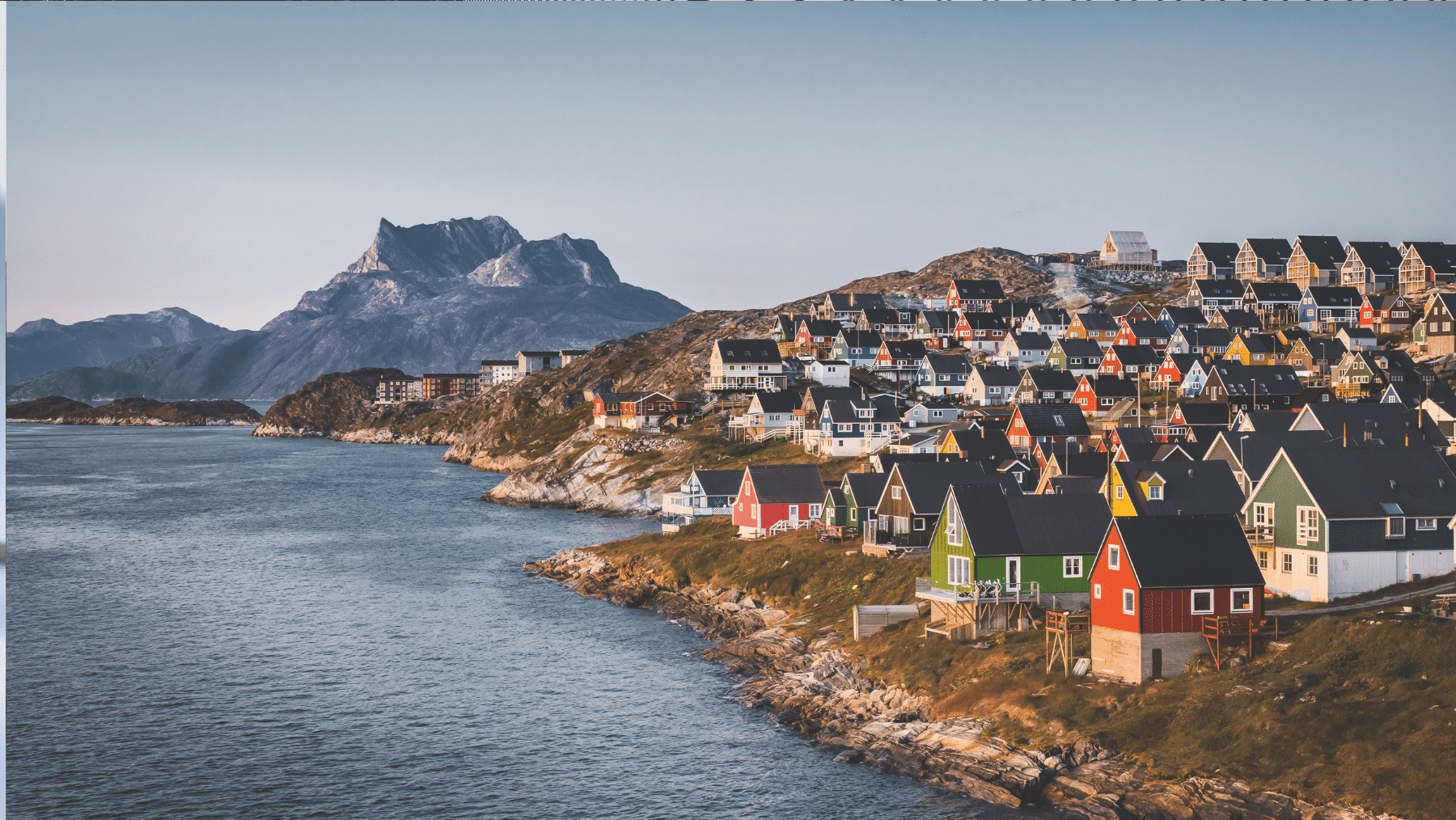 A group of houses on a hill by water