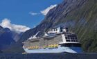 Cruise ship cruises through the mountains at Milford Sound.