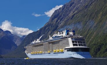 Cruise ship cruises through the mountains at Milford Sound.