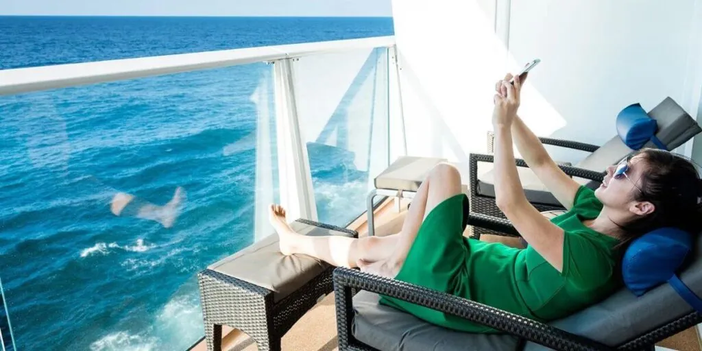 A woman using a phone on her balcony cabin