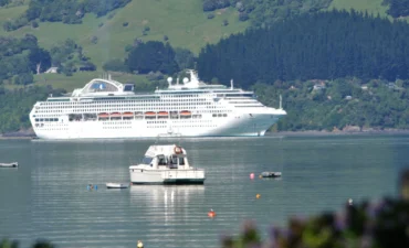 A cruise ship sails across a NZ landscape.