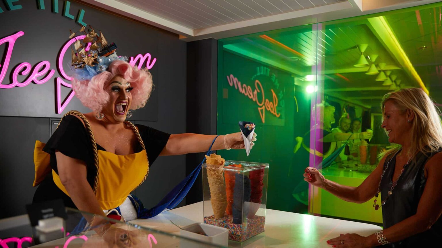 A drag queen handing out ice cream at the Lick Me Till Ice Cream parlour on Virgin Voyages