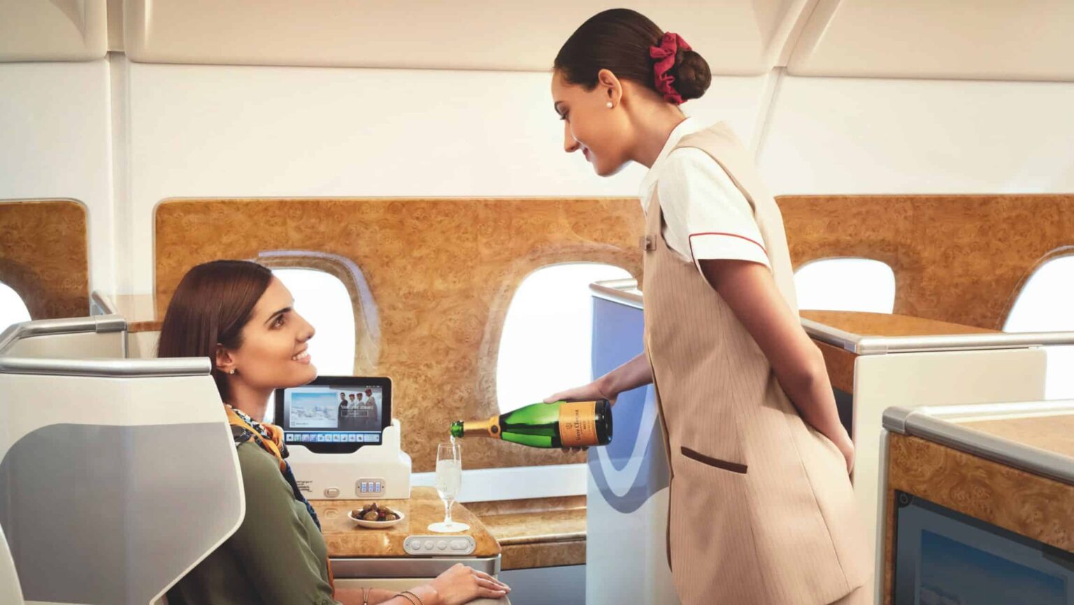 A airline stewardess on Emirates pouring champagn with a passenger