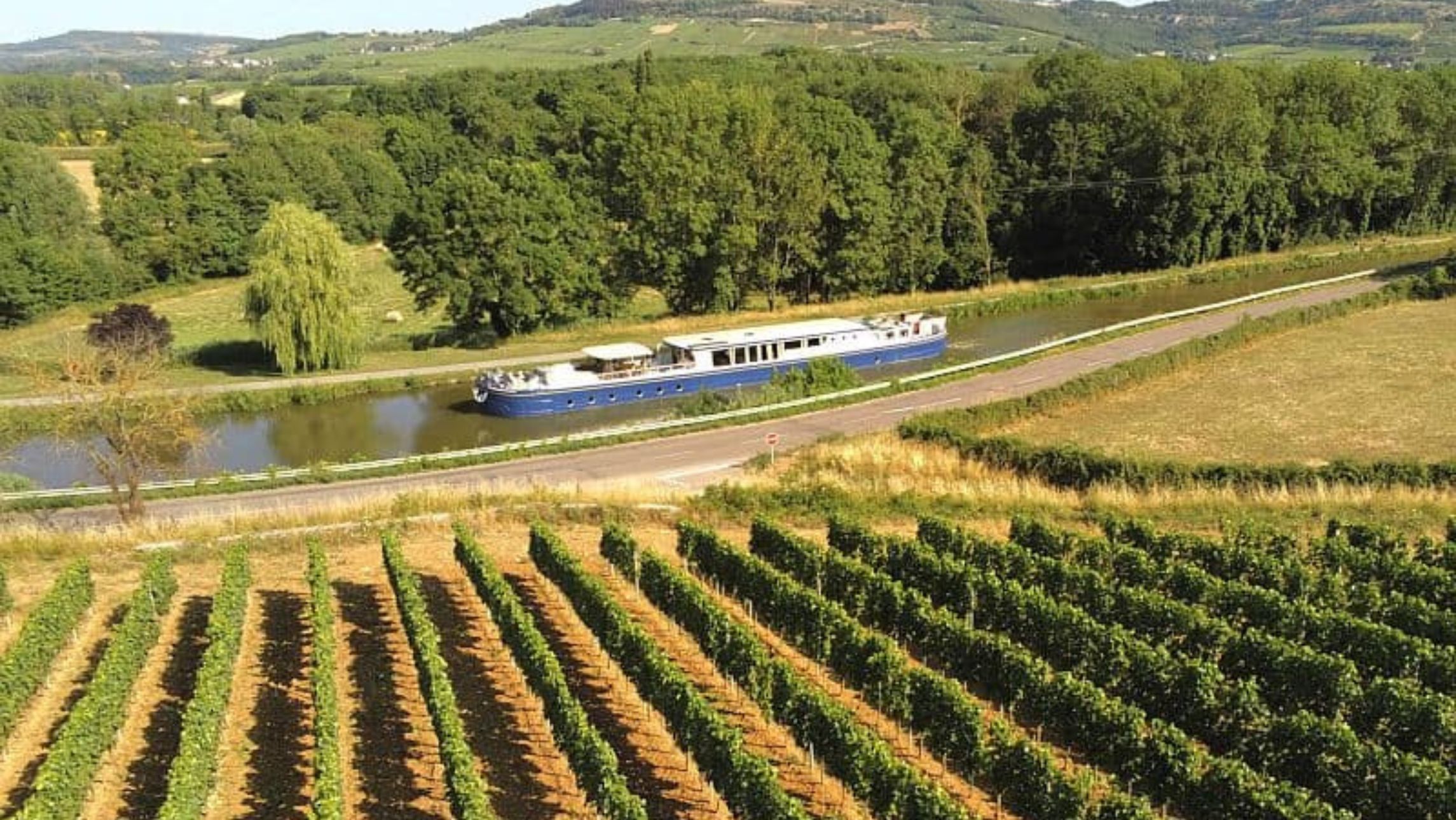 River cruise barge floating past vineyards in Europe for mindful travel