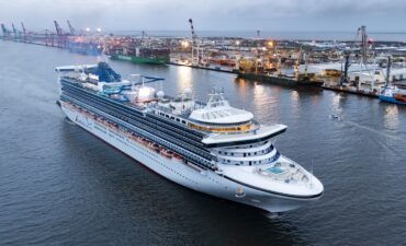 a large cruise ship on the water with a port in the background, Carnival Encounter in Brisbane