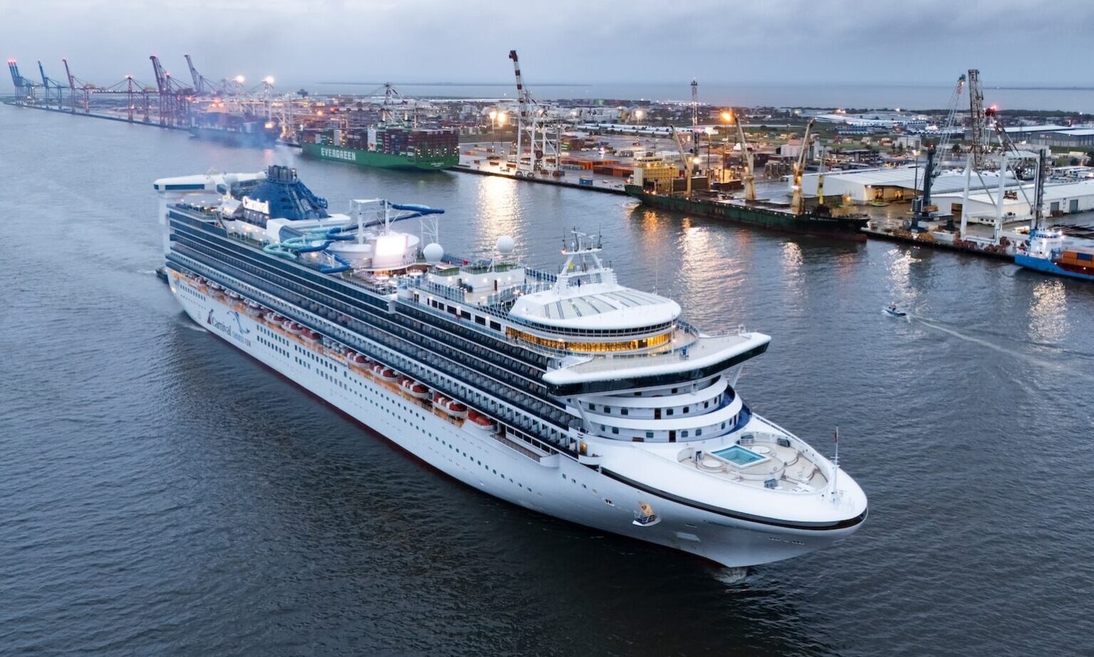 a large cruise ship on the water with a port in the background, Carnival Encounter in Brisbane