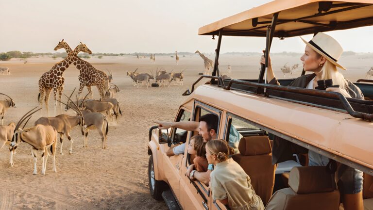 woman and her family in a safari vehicle looking at giraffes