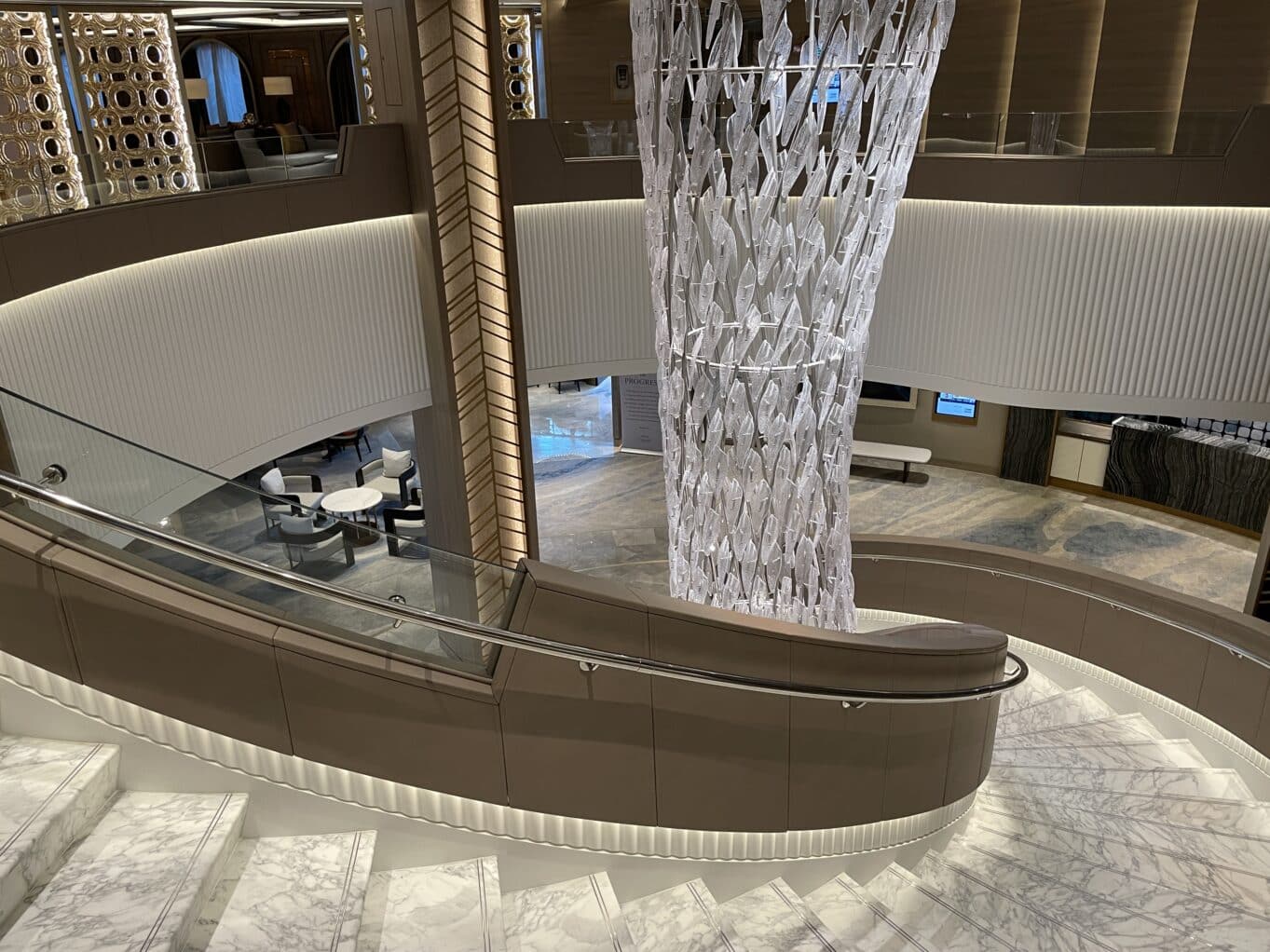 The sweeping staircase and glass sculpture in the atrium on Oceania Allura.