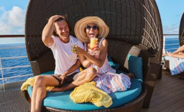 a couple on a cruise ship drinking cocktails and laughing along