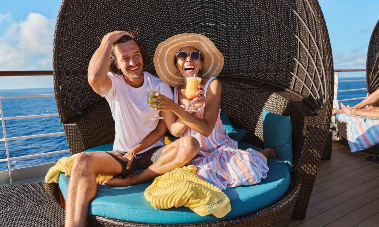 a couple on a cruise ship drinking cocktails and laughing along
