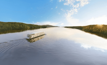 A river cruise vessel sails down wide river