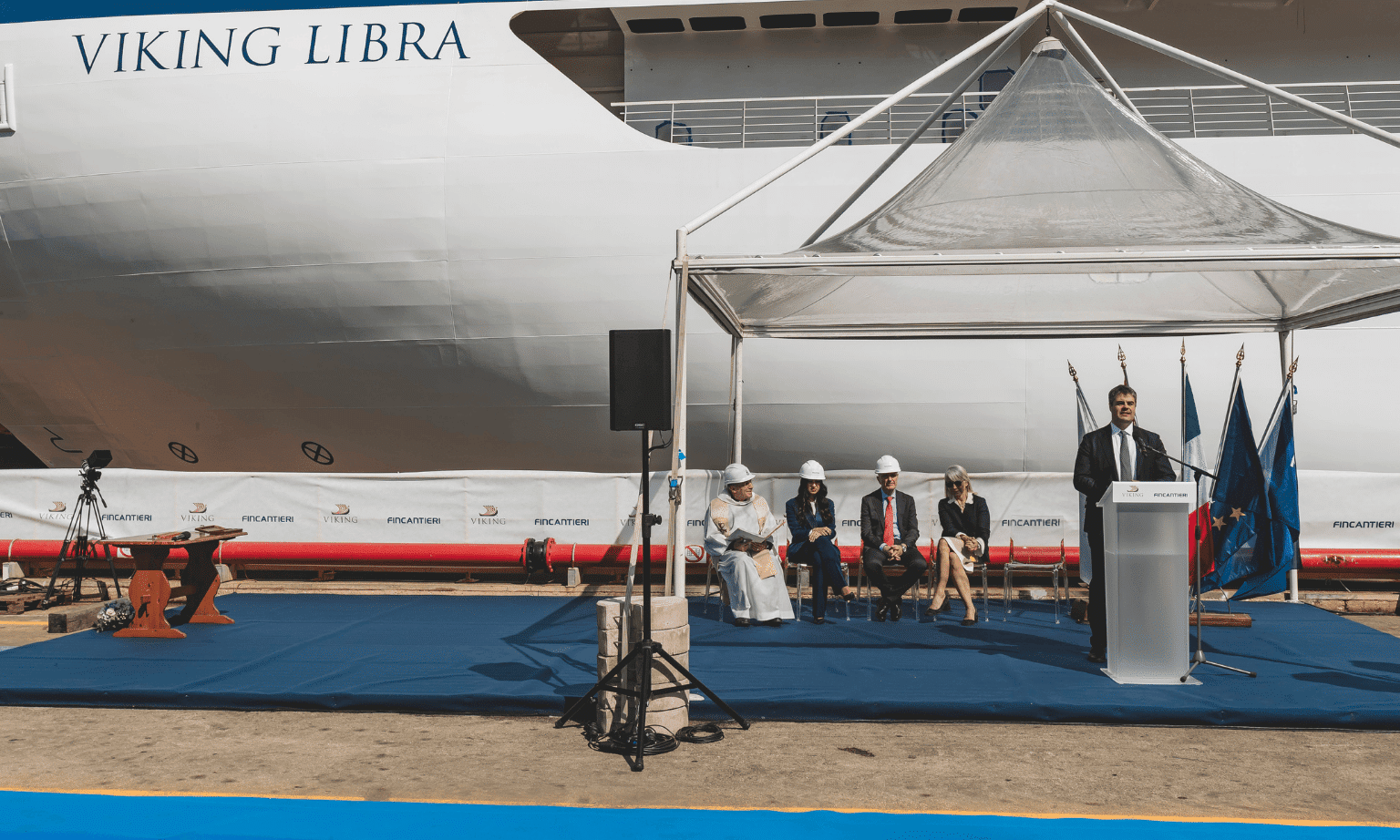 A group of officials sit in front of cruise ship Viking Atlas