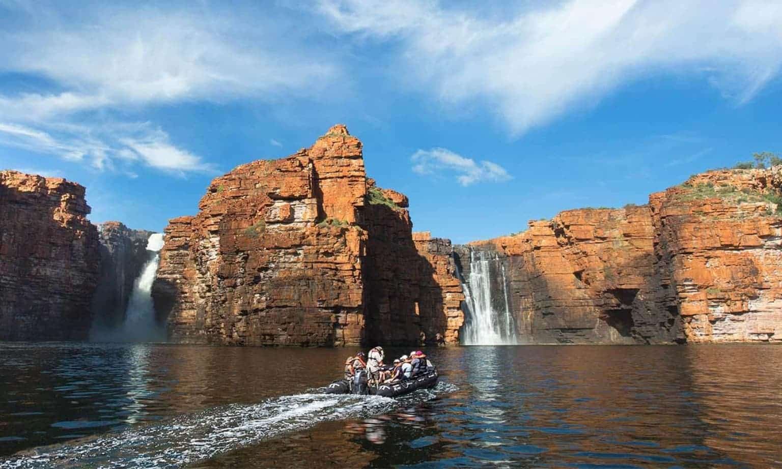 Zodiac boat carrying passengers approaches the towering King George Falls in the Kimberley
