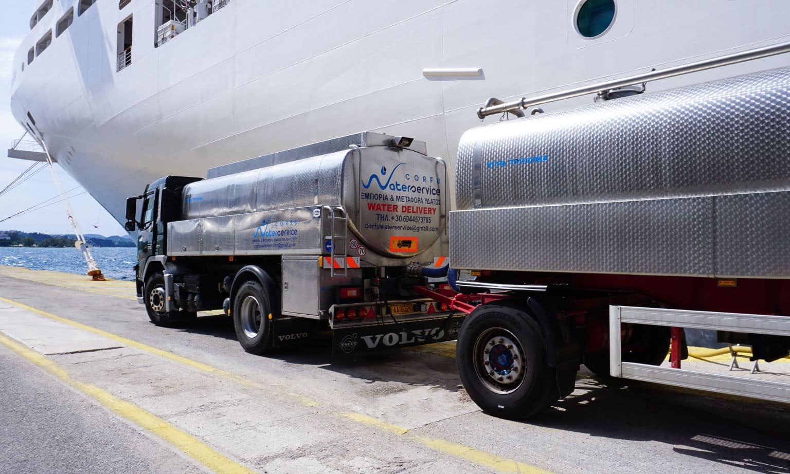 A petrol tanker is parked beside a cruise ship