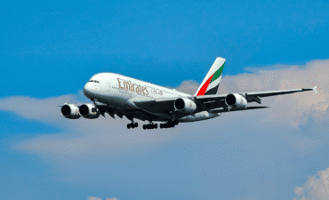Emirates plane flying with clouds and blue sky