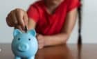 girl putting money into her piggy bank