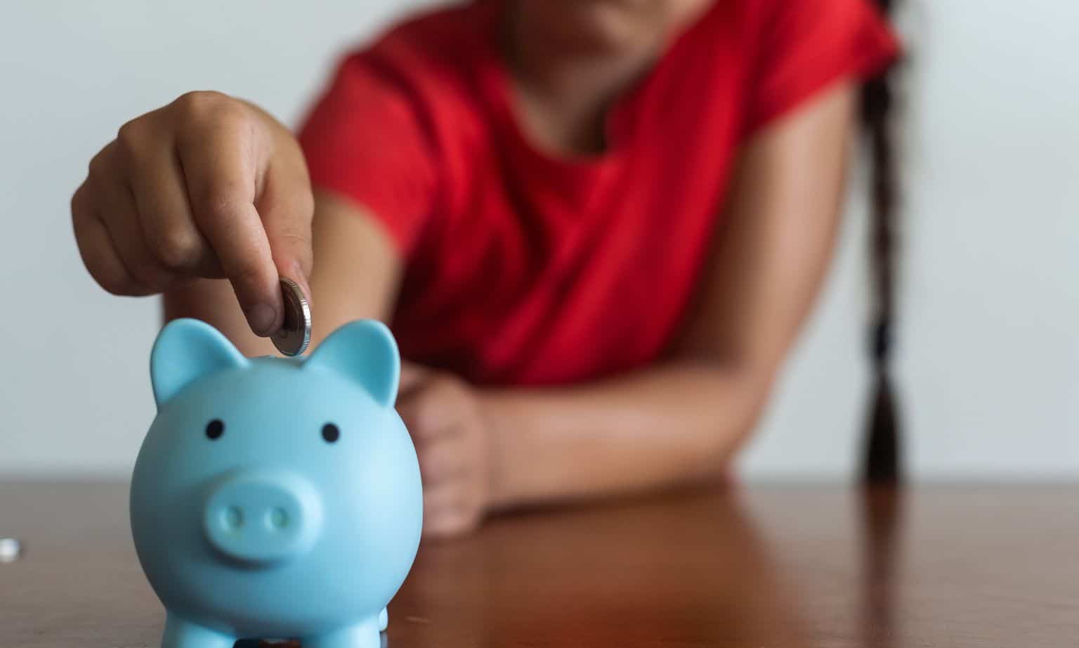 girl putting money into her piggy bank