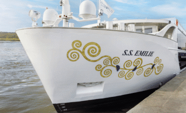 A white cruise ship with gold swirls on the hull on water