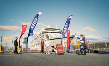 A couple walks on a dock in Eden and is greeted by a cruise ambassador