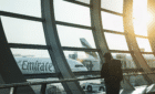 Stock image of a man inside a terminal looking outside to an airplane