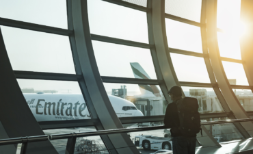 Stock image of a man inside a terminal looking outside to an airplane