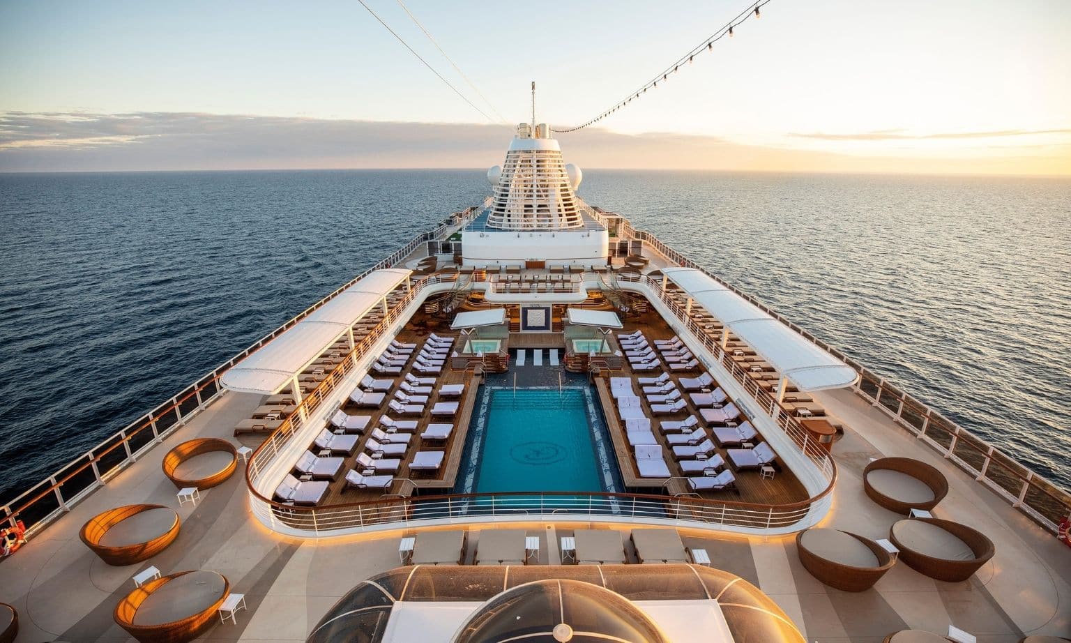 exterior of a cruise ship showing a pool and deck chairs