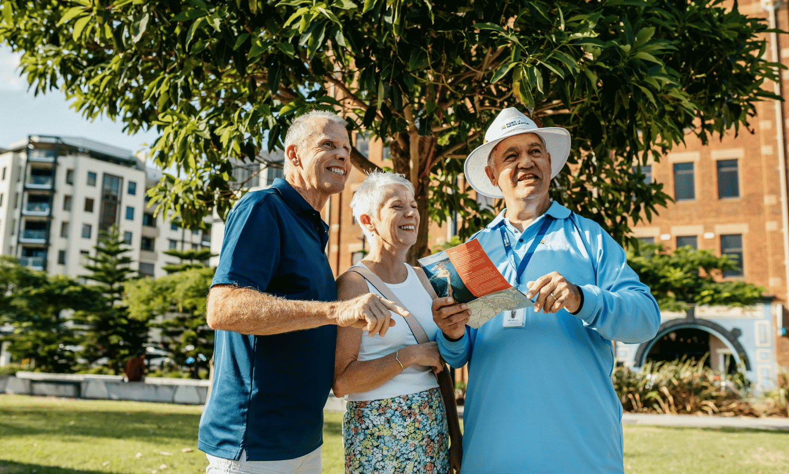 A volunteer cruise ambassador shows two grey haired tourists a map of the city of Newcastle